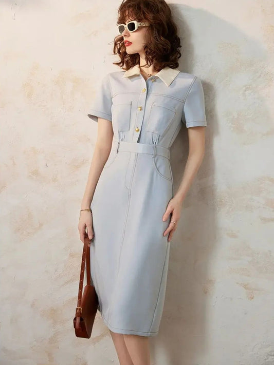 Woman wearing light blue short-sleeve midi dress with white collar and brown handbag