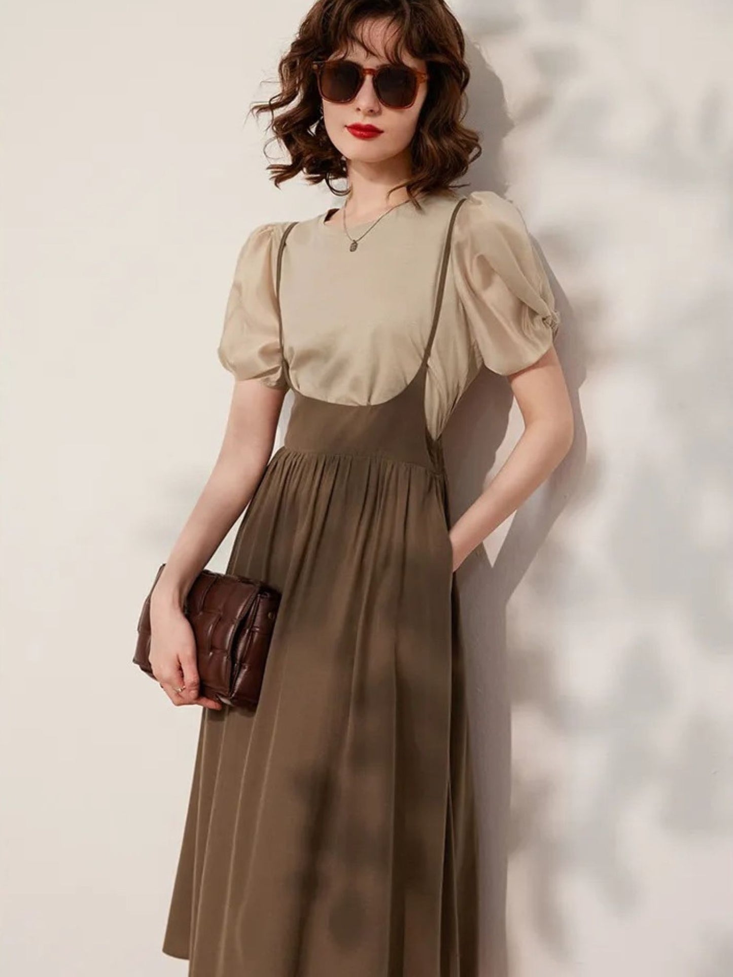 Woman posing in beige blouse tucked into brown skirt
