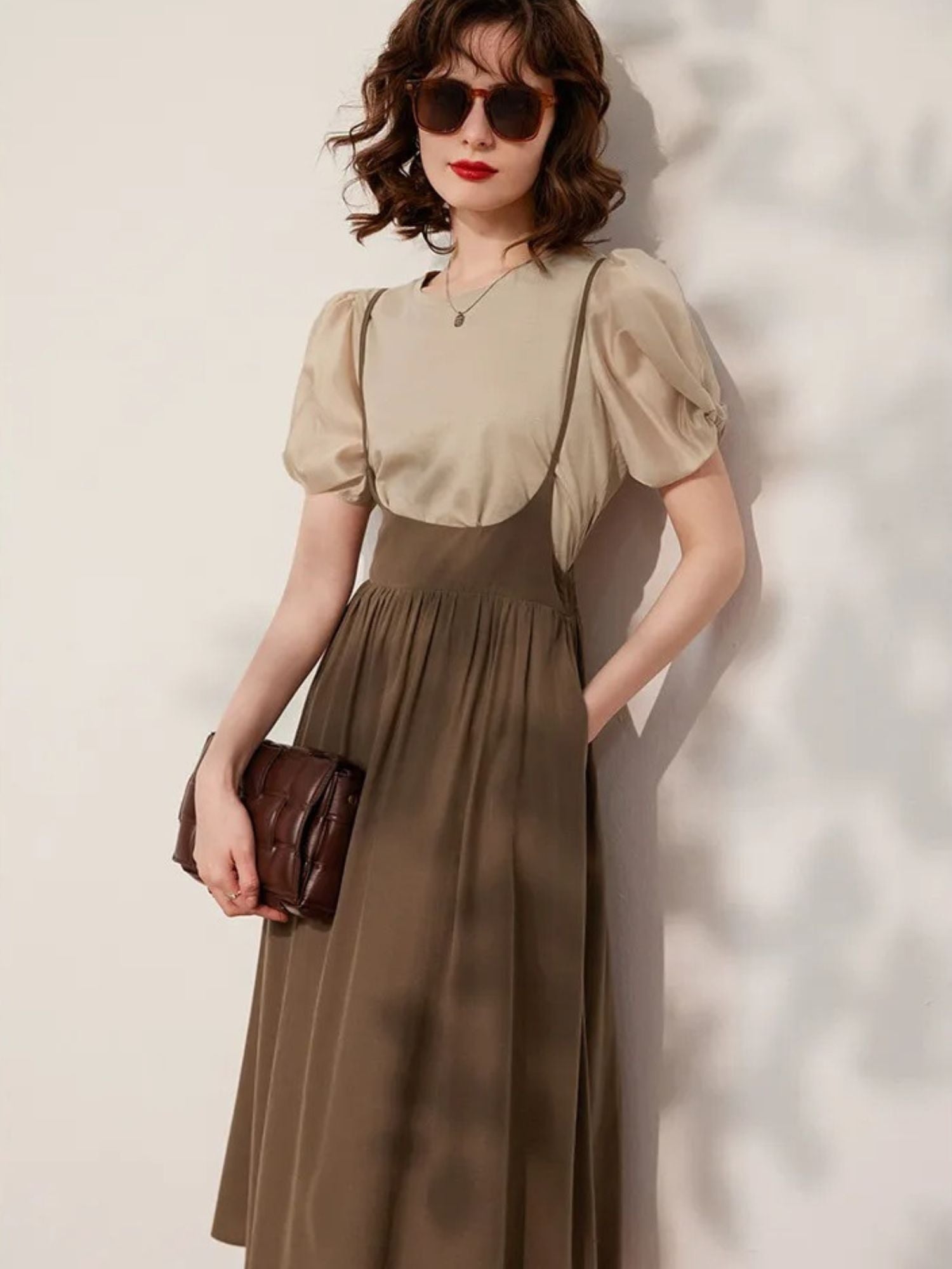 Woman posing in beige blouse tucked into brown skirt