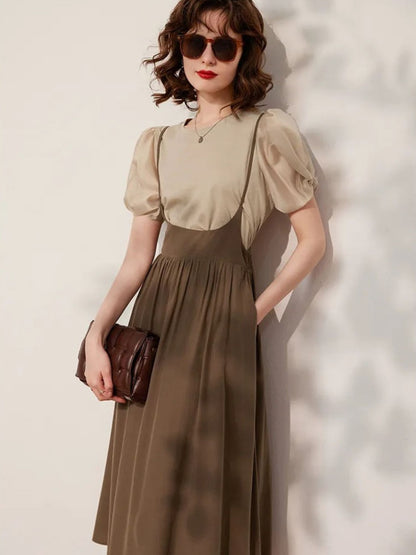 Woman posing in beige blouse tucked into brown skirt