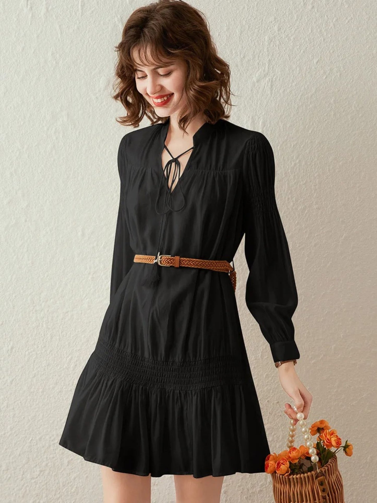 Front view of black pleated mini dress with belt and long sleeves