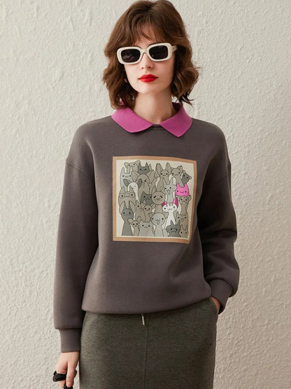 Woman wearing a grey sweatshirt with graphic print on the front, styled with a pink collared shirt and pencil skirt