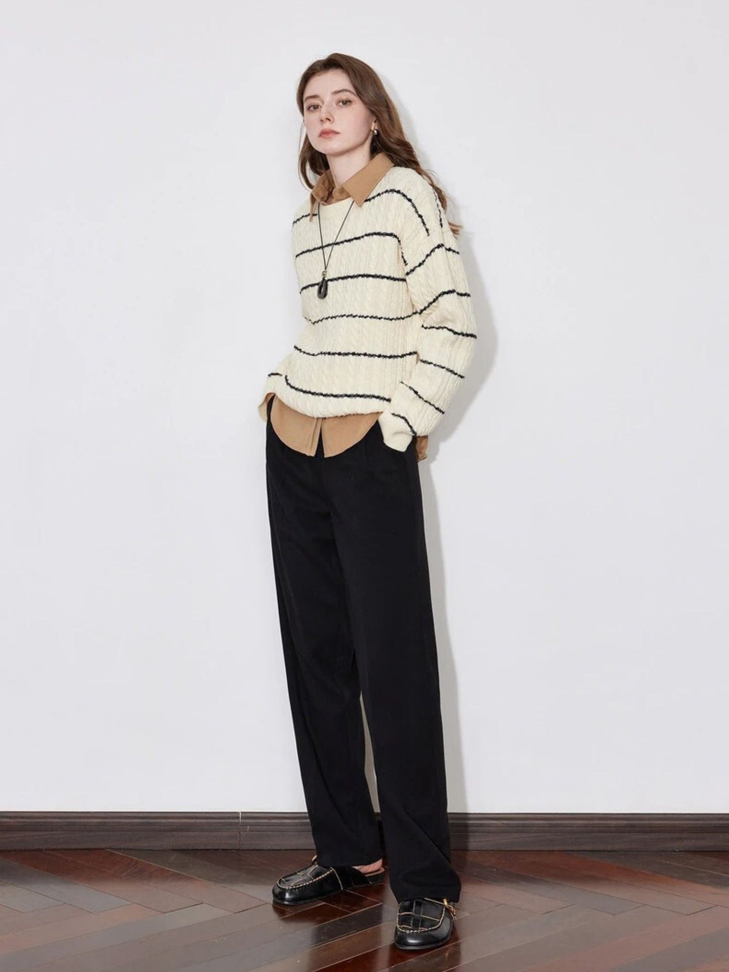 A model wearing a lose striped sweater with a pair of black lose pants
