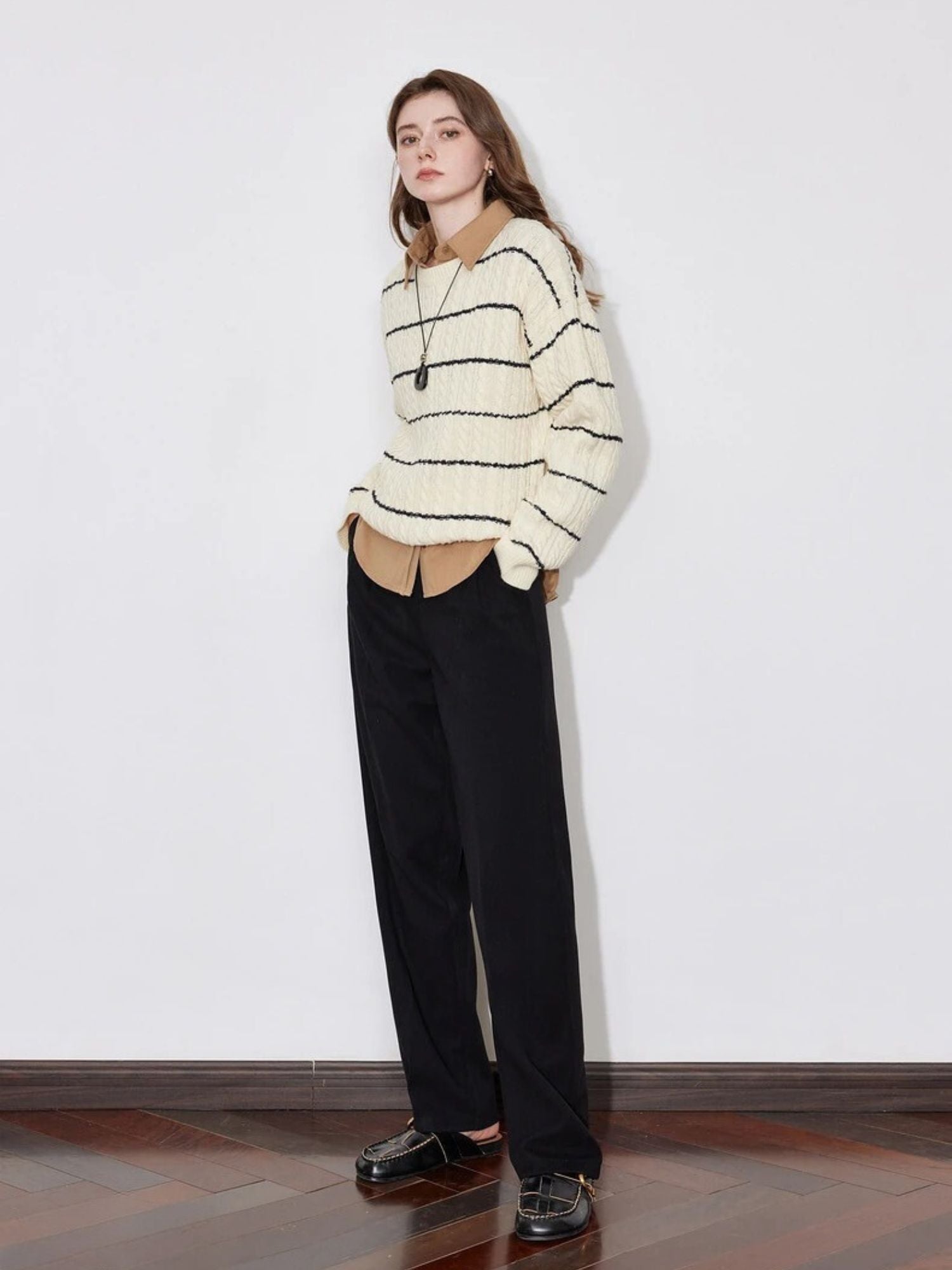 A model wearing a lose striped sweater with a pair of black lose pants