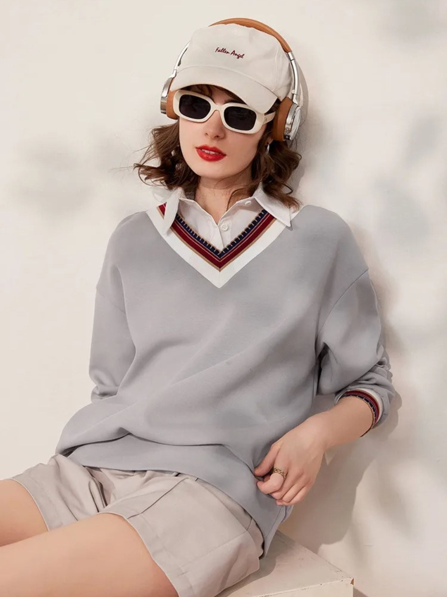 A woman wearing a grey sweater with a layered polo v-neck design paired