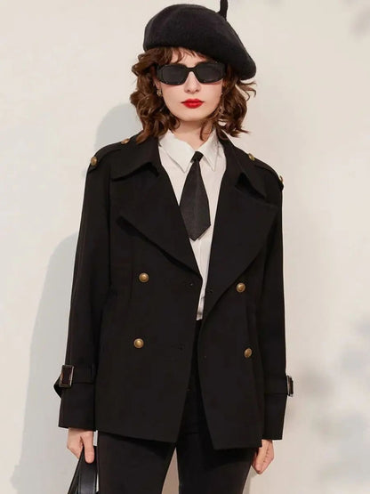 Full-body view of woman in black blazer and trousers, white shirt with tie, and beret, posing with hands in pockets