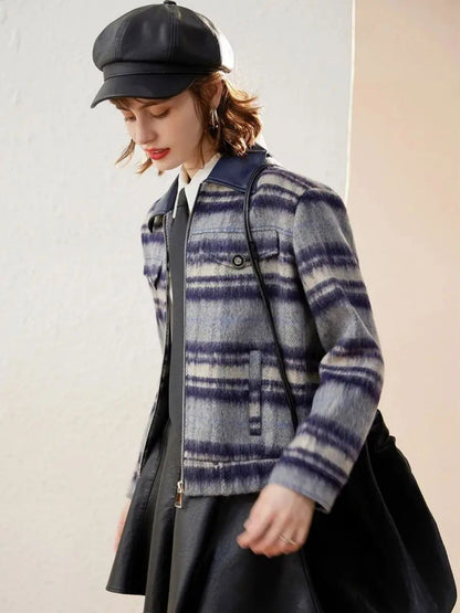 Side view of woman in plaid jacket, white shirt, and black skirt, posing with hand in pocket