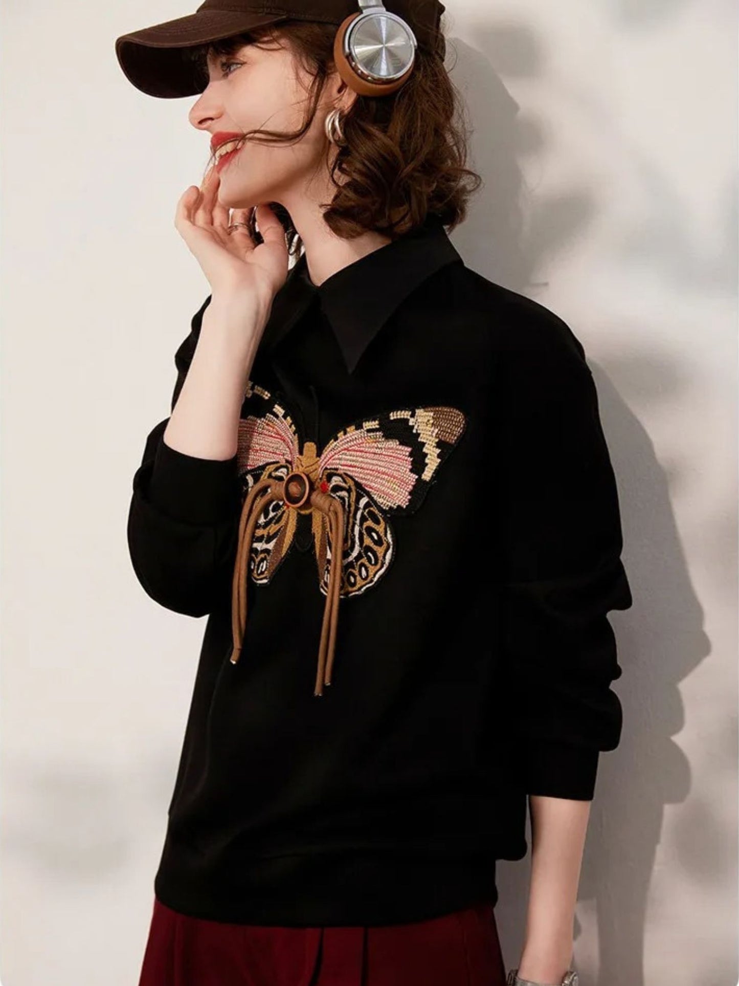 Side view of black embroidered sweatshirt paired with red trousers