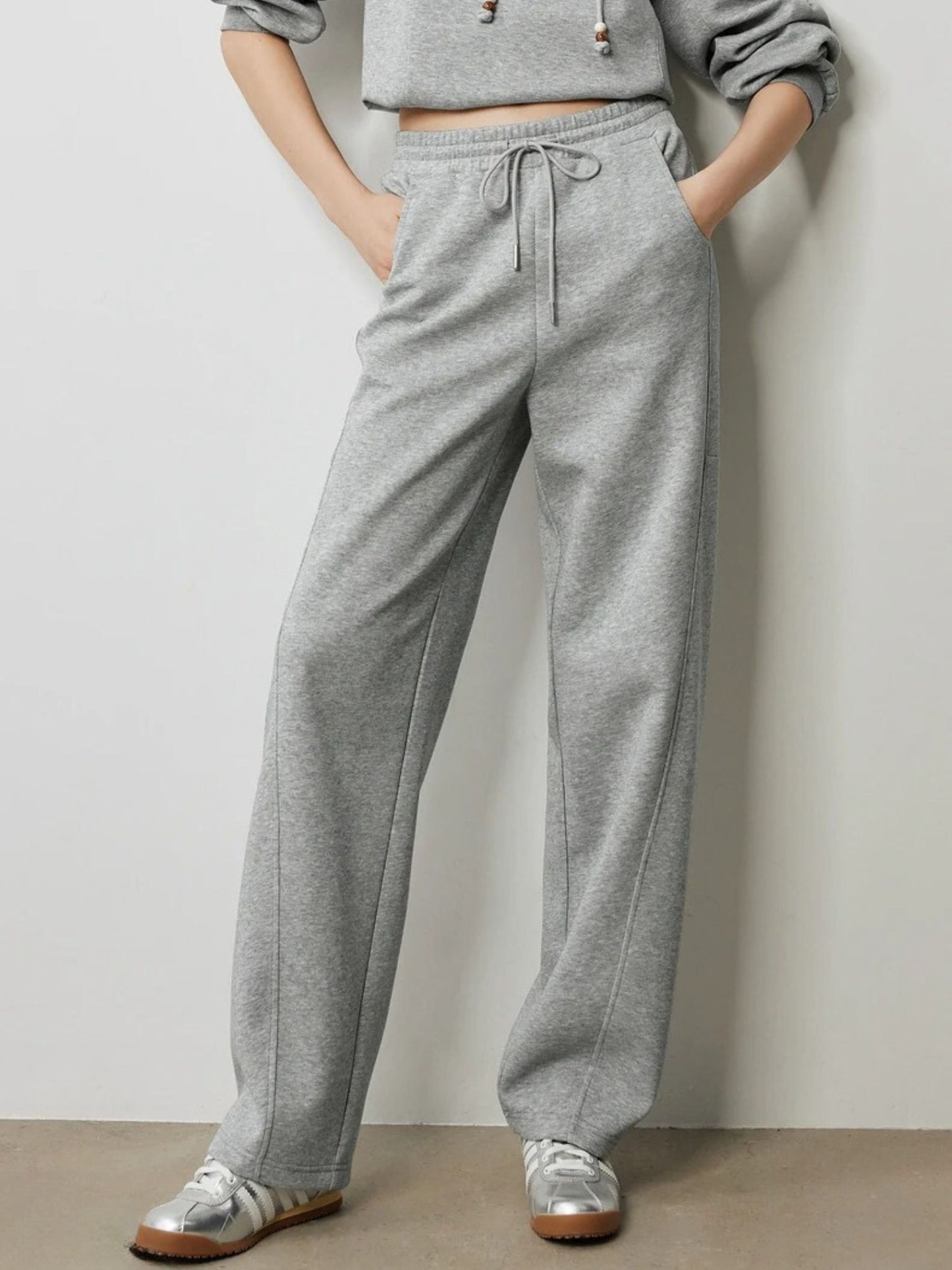 Close-up of grey drawstring trousers with elastic waistband and pockets