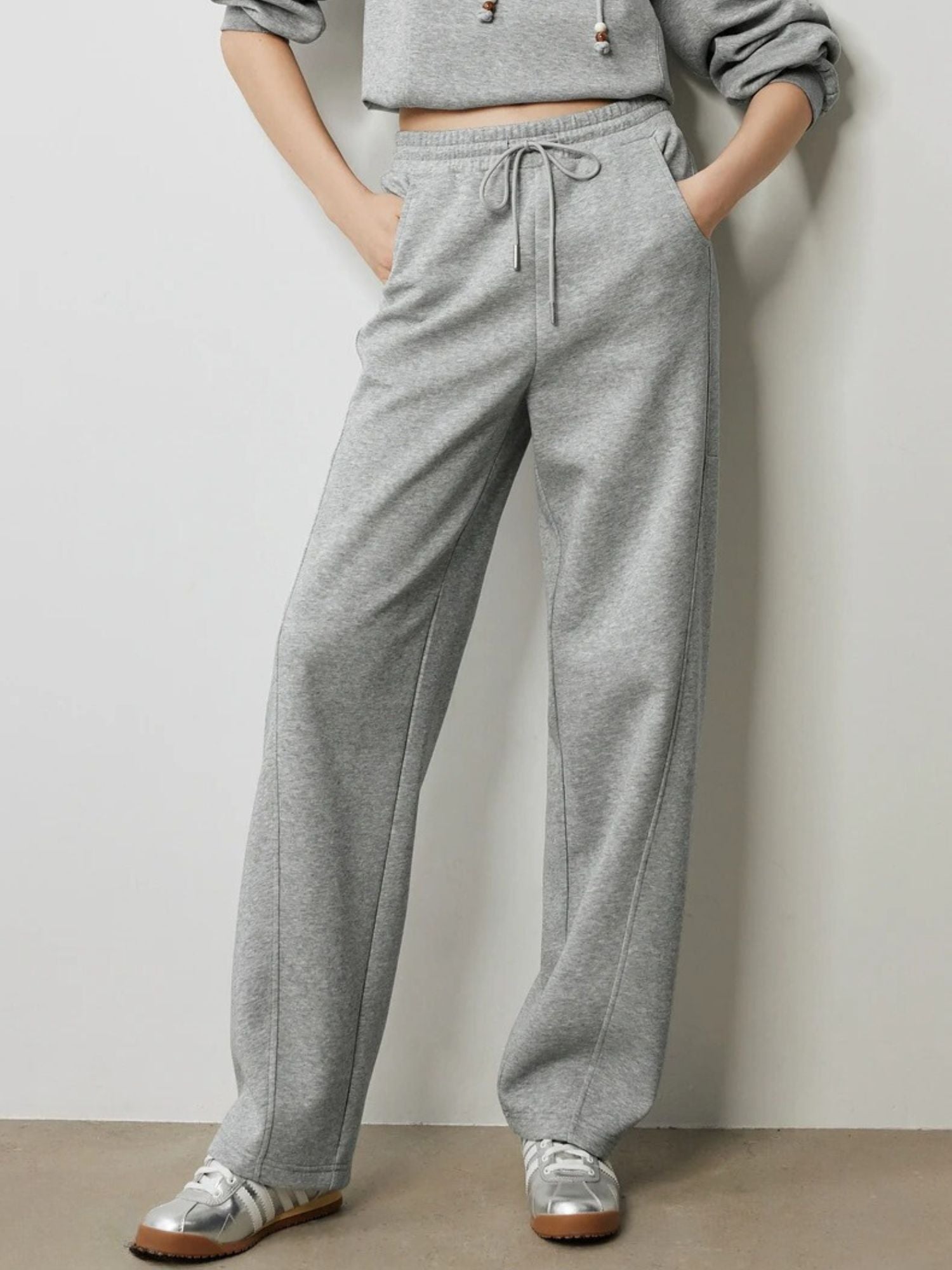 Close-up of grey drawstring trousers with elastic waistband and pockets