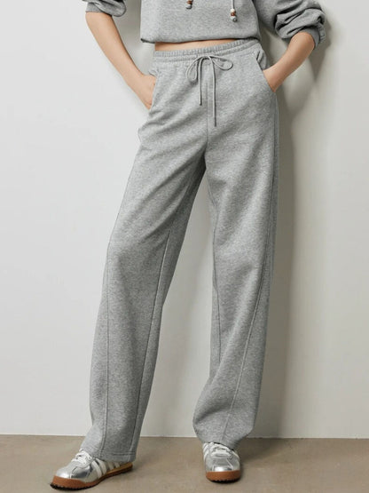 Close-up of grey drawstring trousers with elastic waistband and pockets