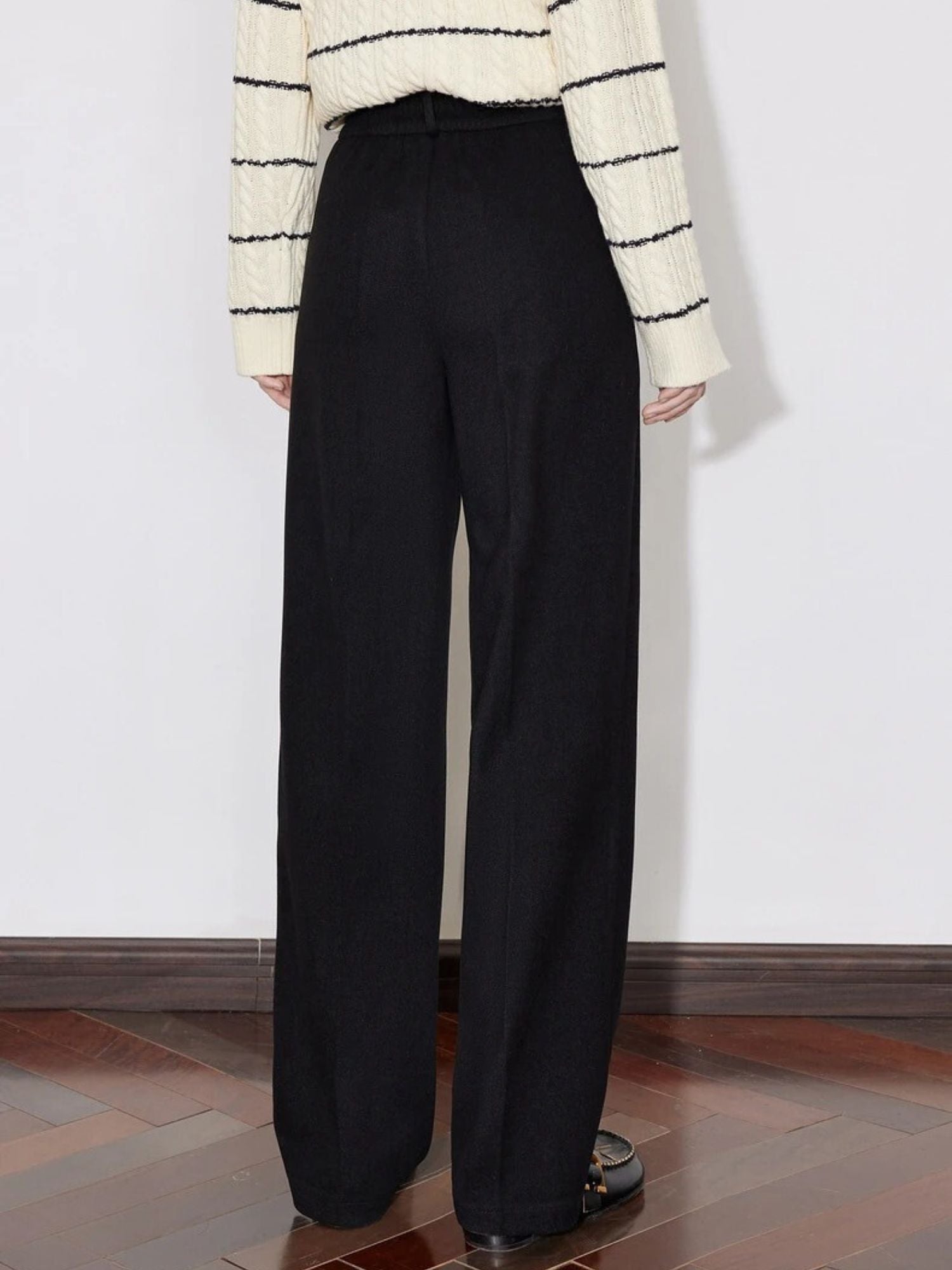 Back view of black wide-leg trousers styled with striped sweater and loafers