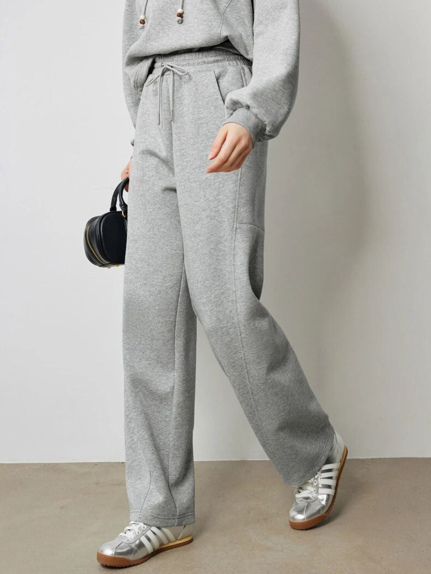 A young woman wearing a gray drawstring hoodie paired with gray drawstring high-waisted pants
