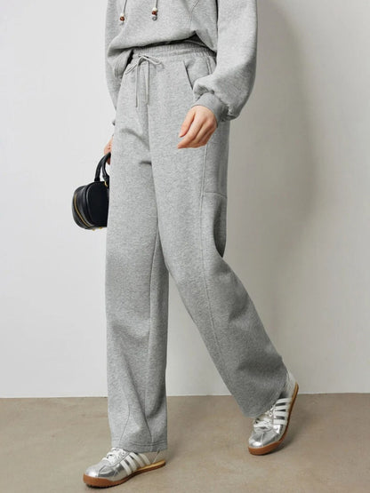 A young woman wearing a gray drawstring hoodie paired with gray drawstring high-waisted pants