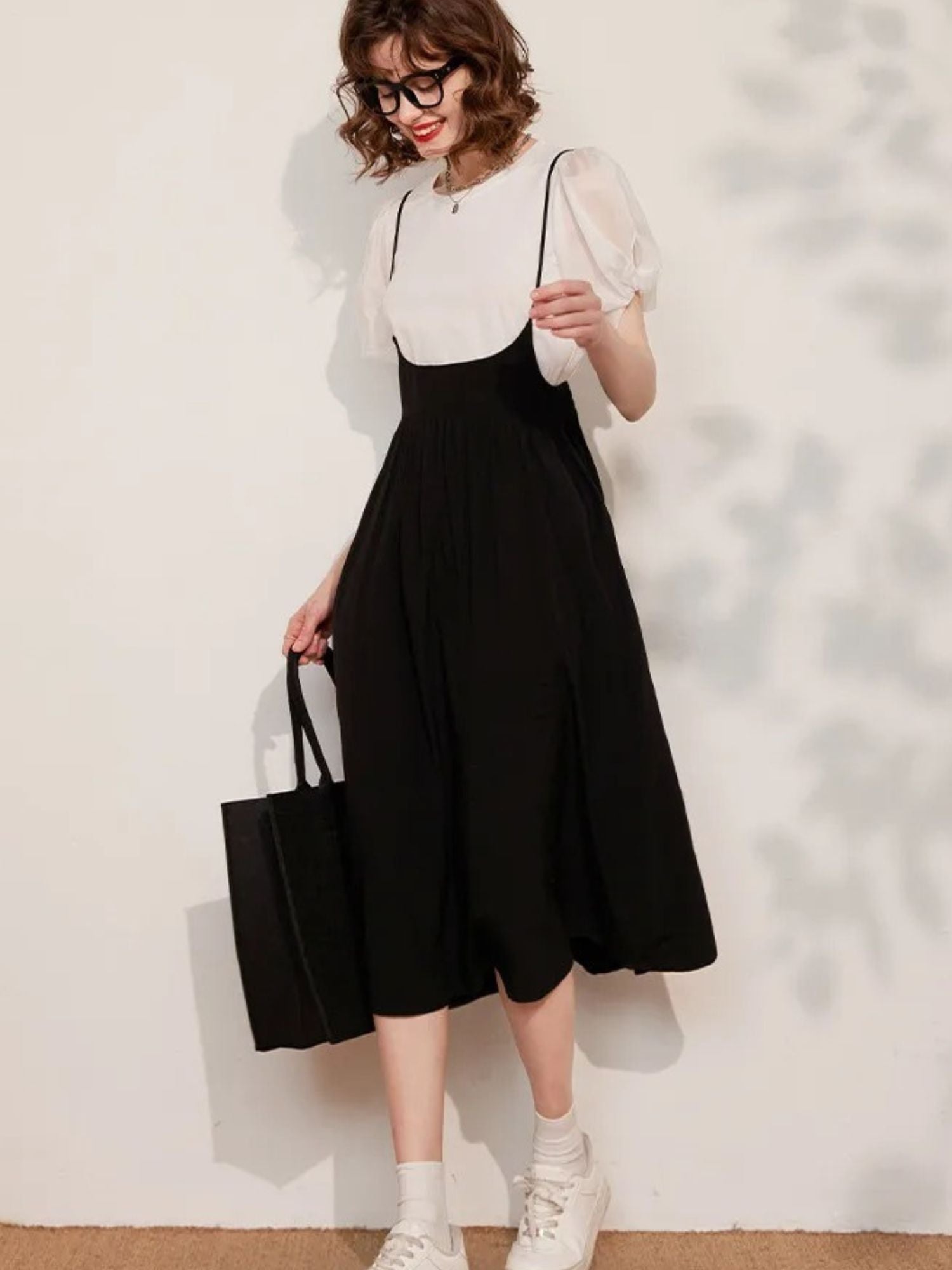 Side angle of cream blouse with puff sleeves and black pleated skirt