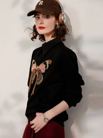 Woman in black embroidered sweatshirt, smiling and facing forward