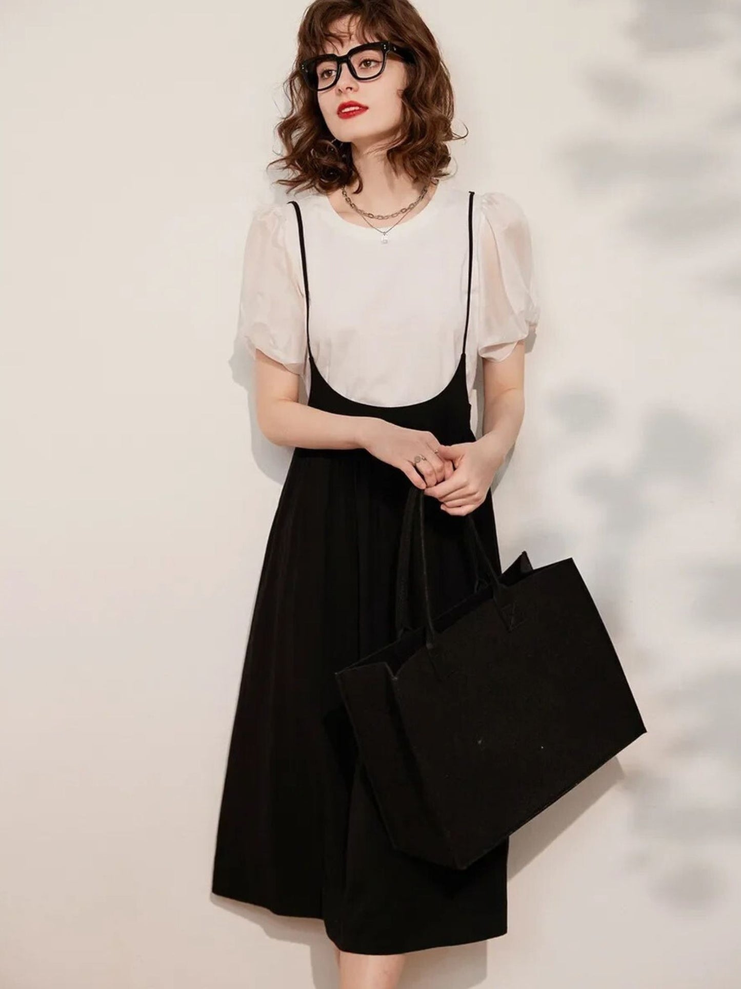 Full-body view of cream blouse and black midi skirt outfit with handbag