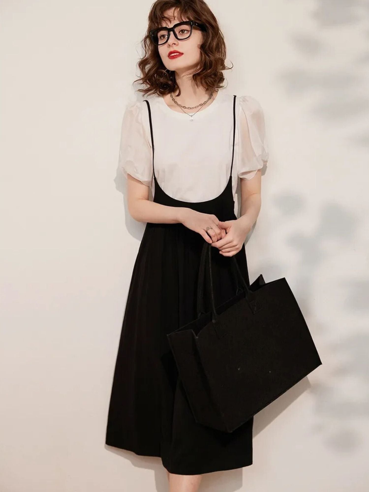 Full-body view of cream blouse and black midi skirt outfit with handbag