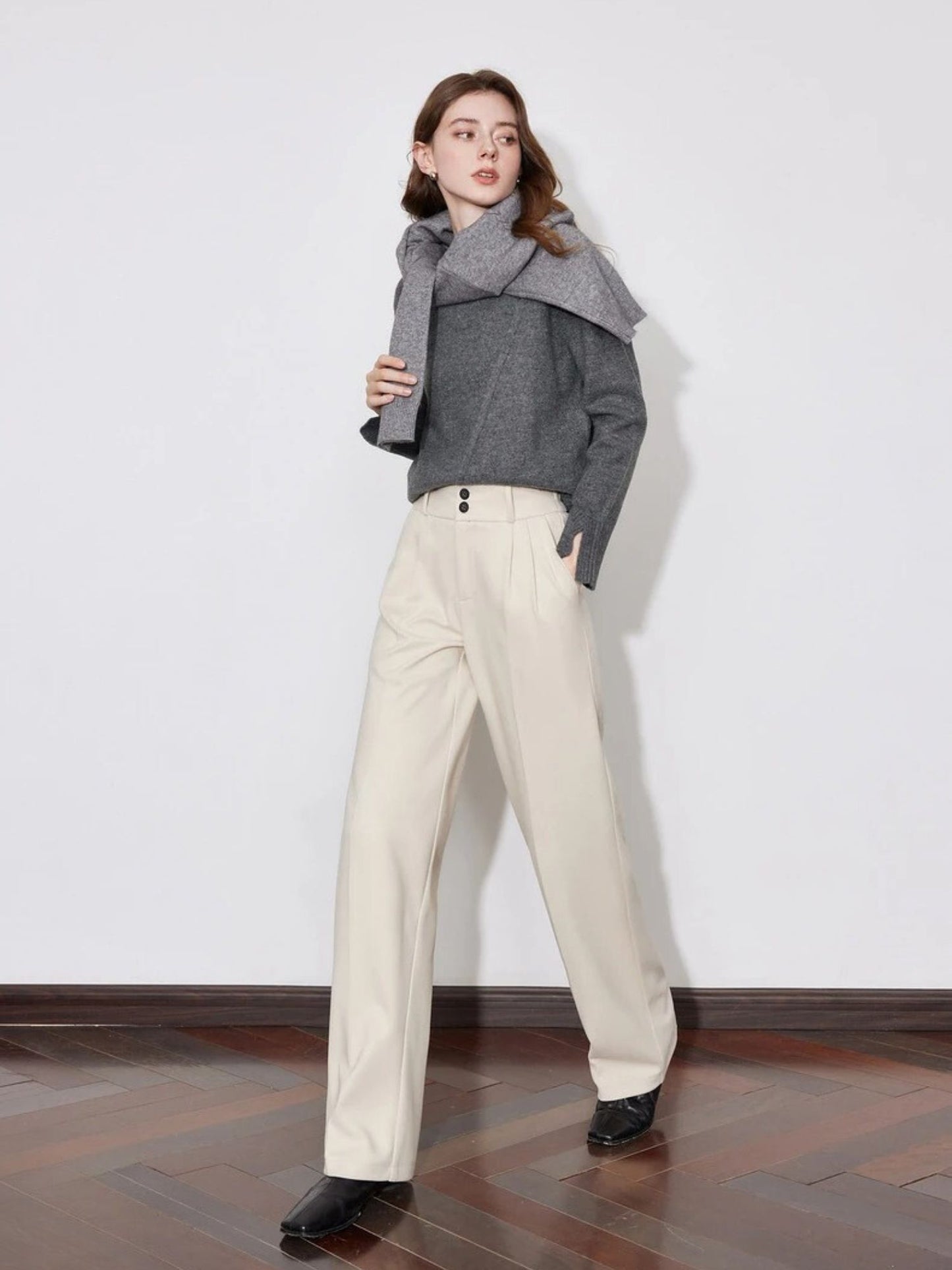 Woman in ivory wide-leg trousers with grey sweater and black shoes