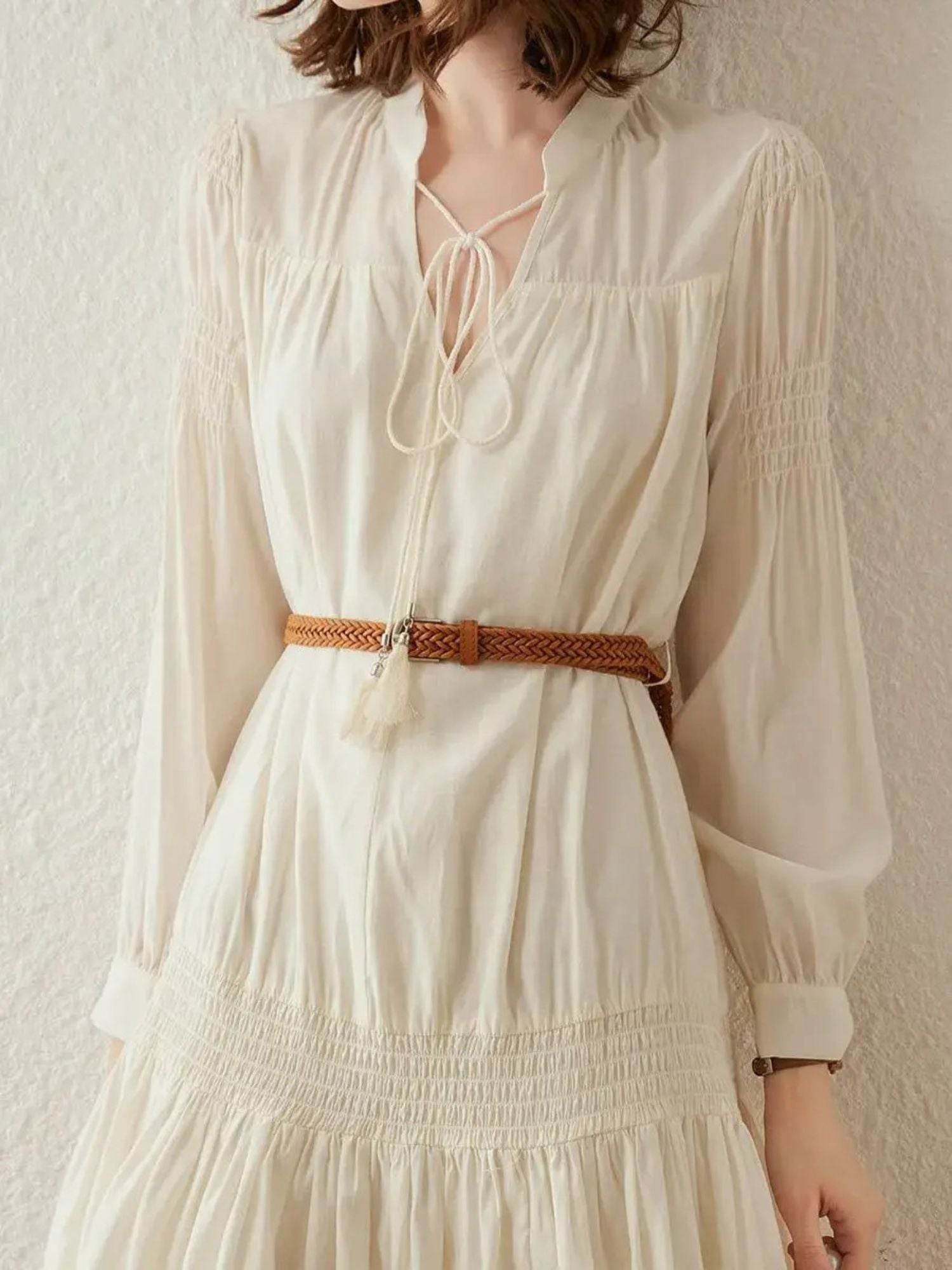 Close-up of cream pleated dress showing braided brown belt detail