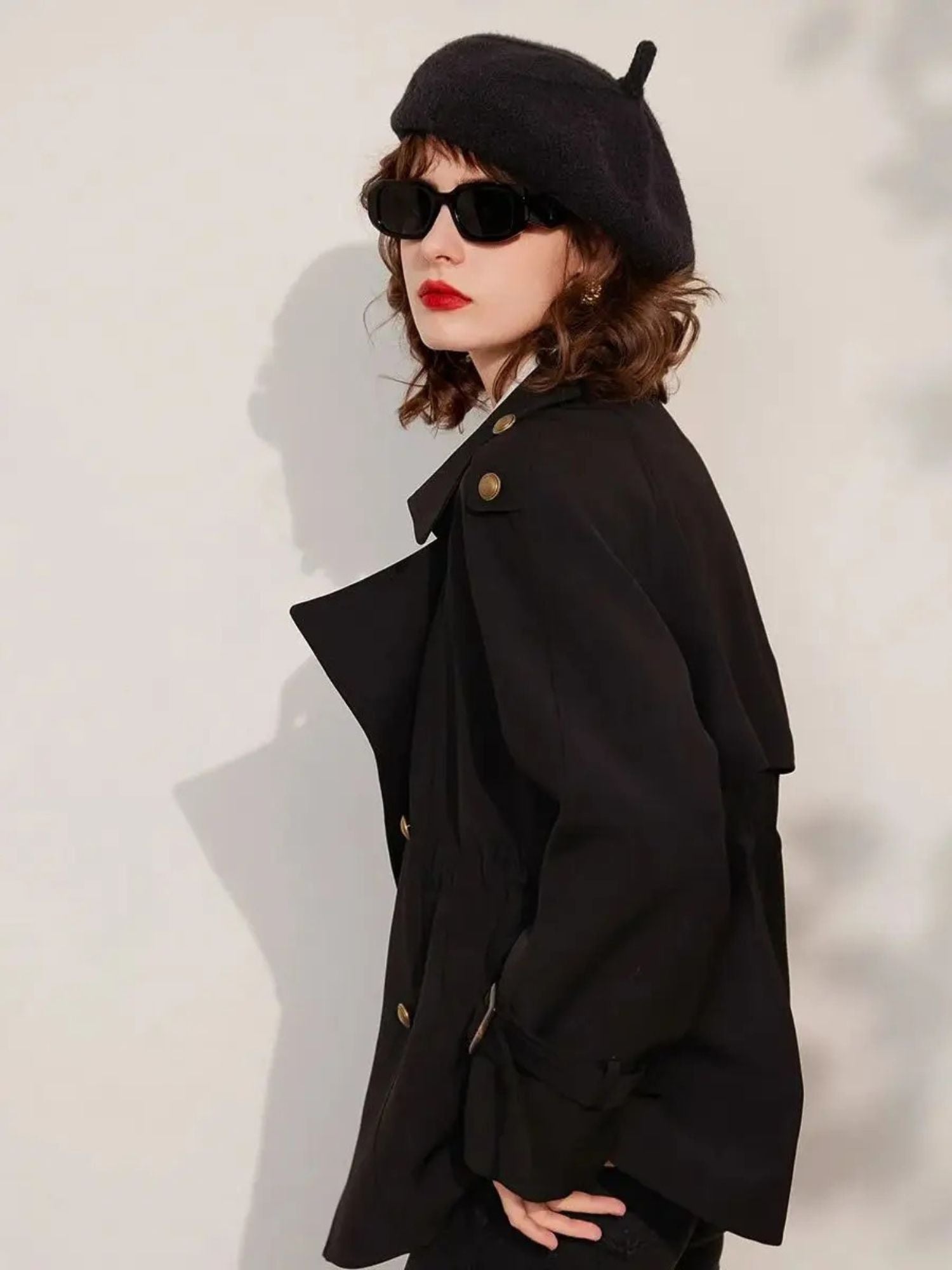 Side view of woman in black blazer and trousers, with beret and sunglasses