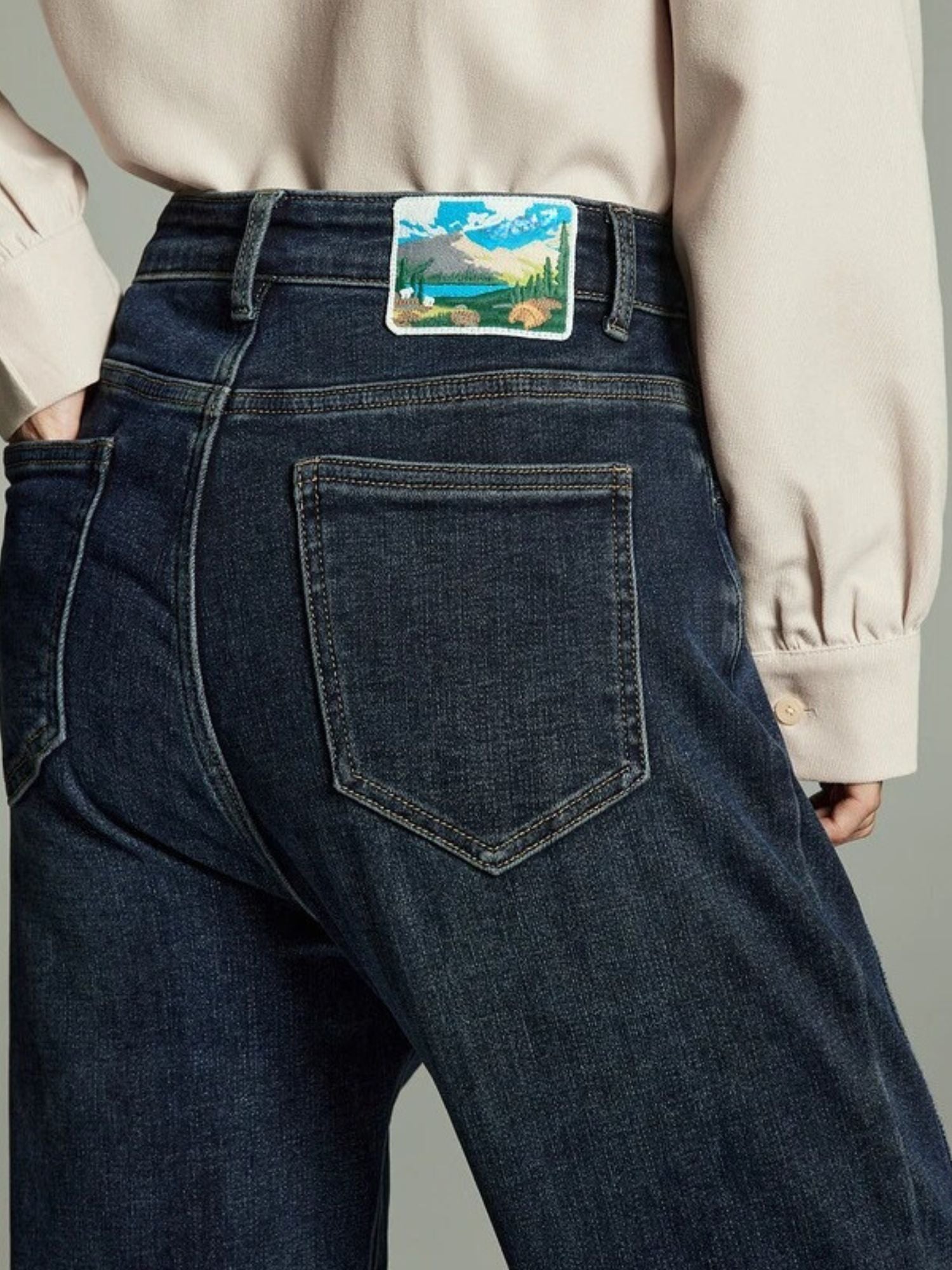 Back view of a pair of high-waisted, straight cut denim jeans with embroidered detailing