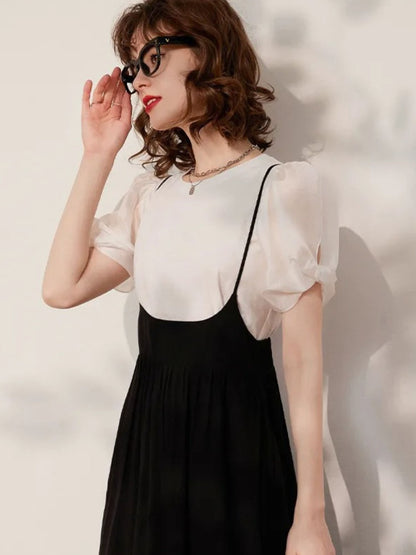 Woman adjusting glasses while wearing cream blouse and black midi skirt