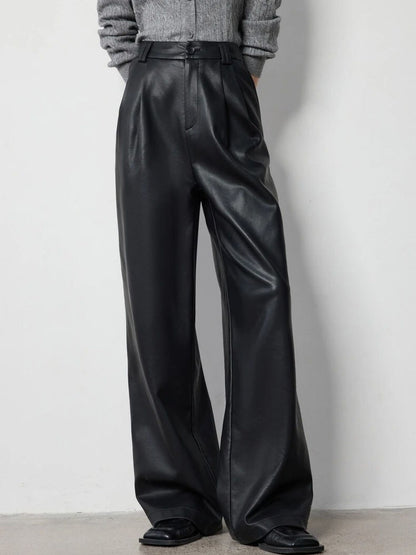 Full-length view of black faux leather pants styled with grey knit top and boots