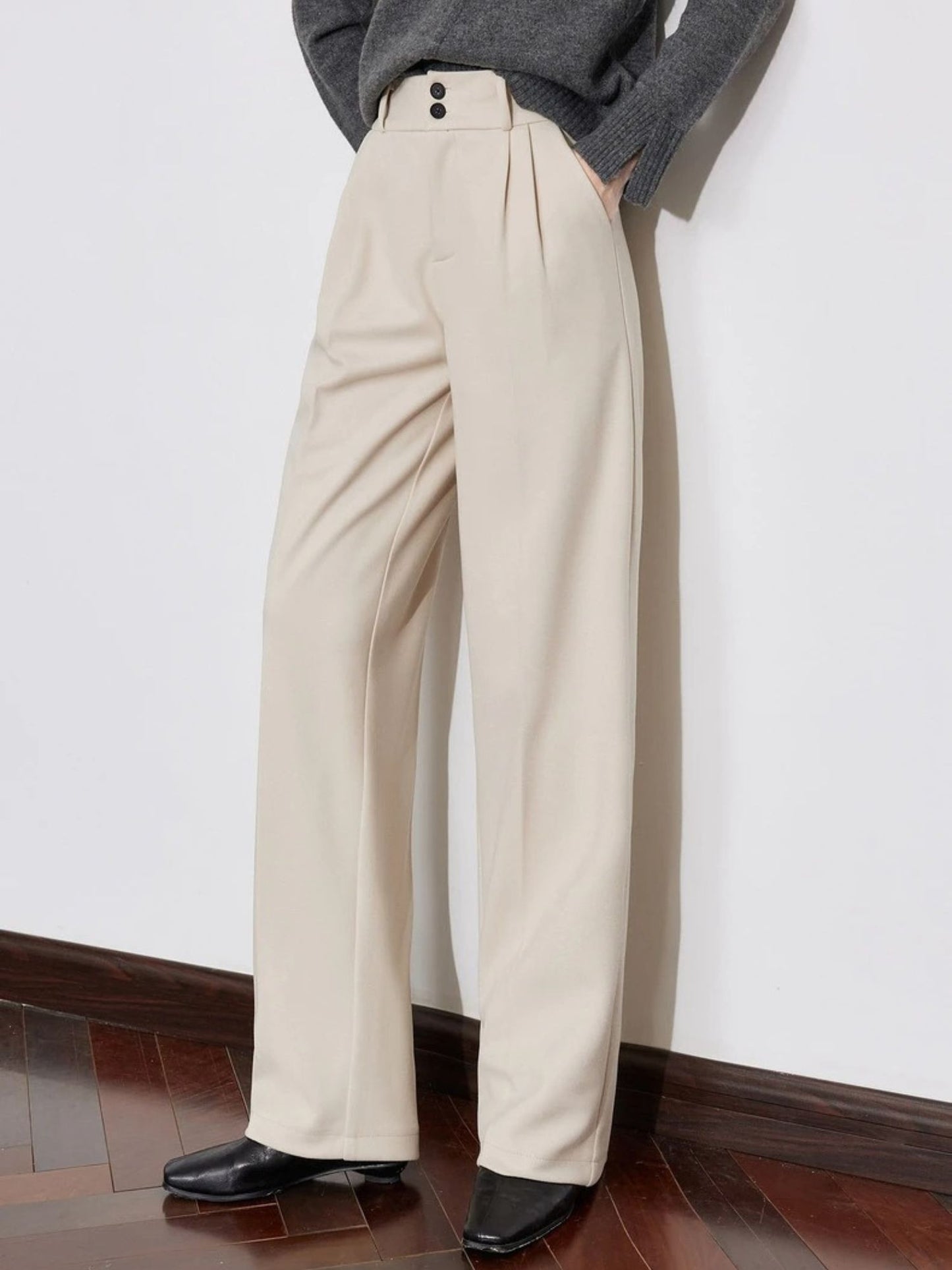 Close-up of ivory wide-leg trousers with grey sweater and black shoes