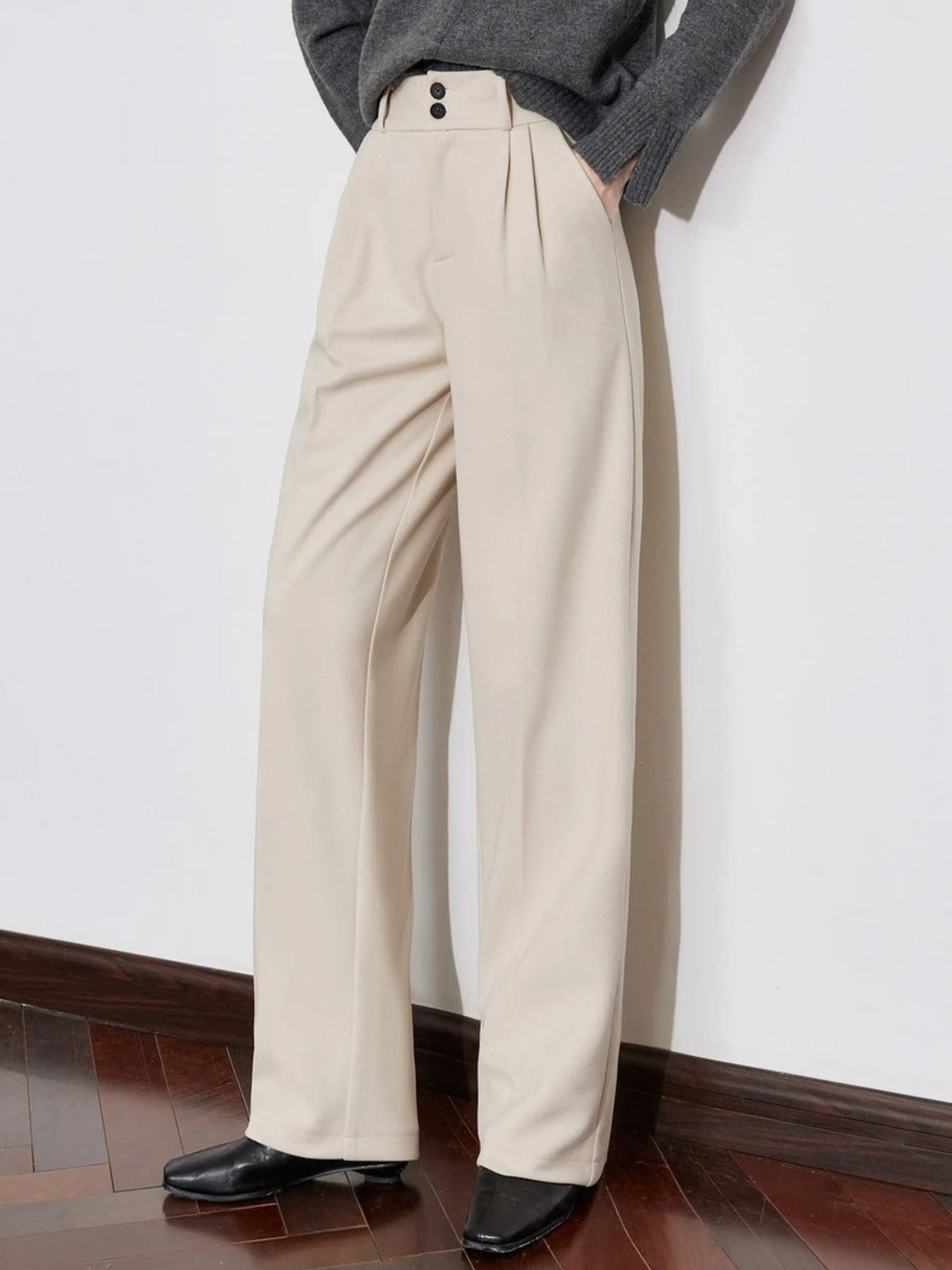 Close-up of ivory wide-leg trousers with grey sweater and black shoes