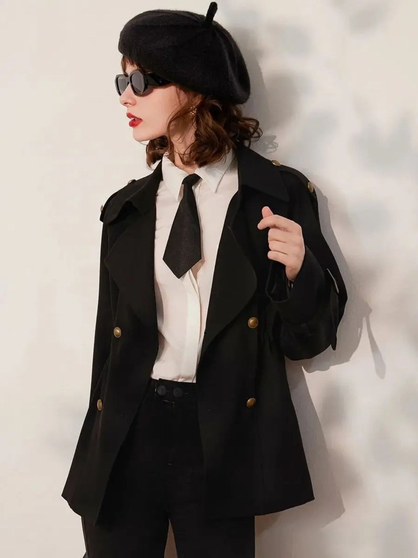 Back view of woman wearing black blazer and trousers, styled with beret