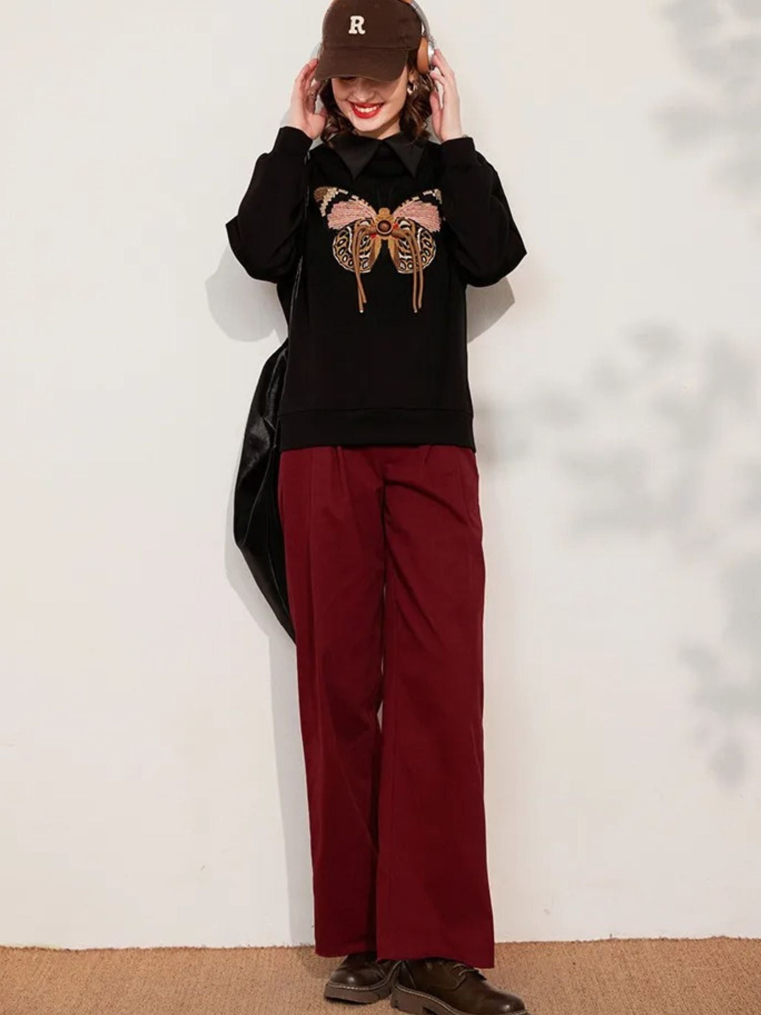 Full body view of butterfly embroidery detail on sweatshirt, showing pink and gold tones