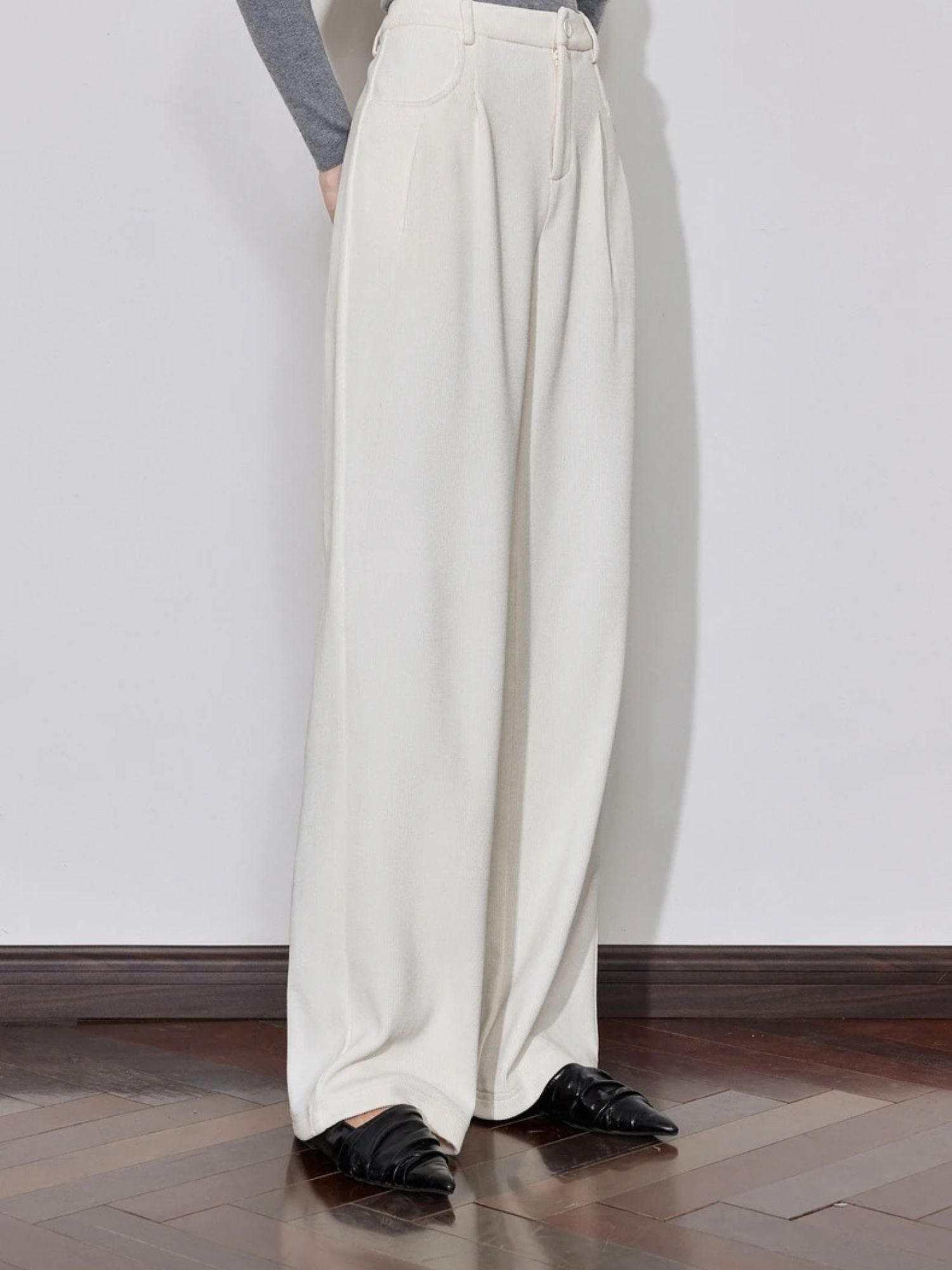 Side view of ivory wide-leg trousers styled with grey top and black shoes