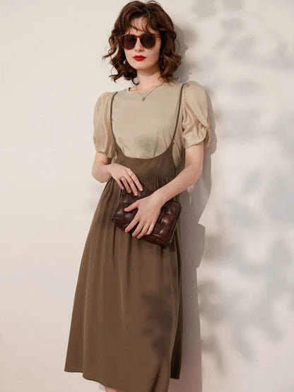 Woman wearing beige puff-sleeve blouse tucked into brown midi skirt, holding handbag