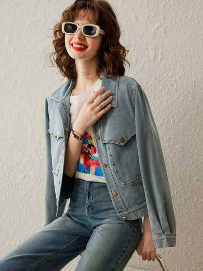 Woman wearing light blue denim jacket over a printed t-shirt, smiling while seated