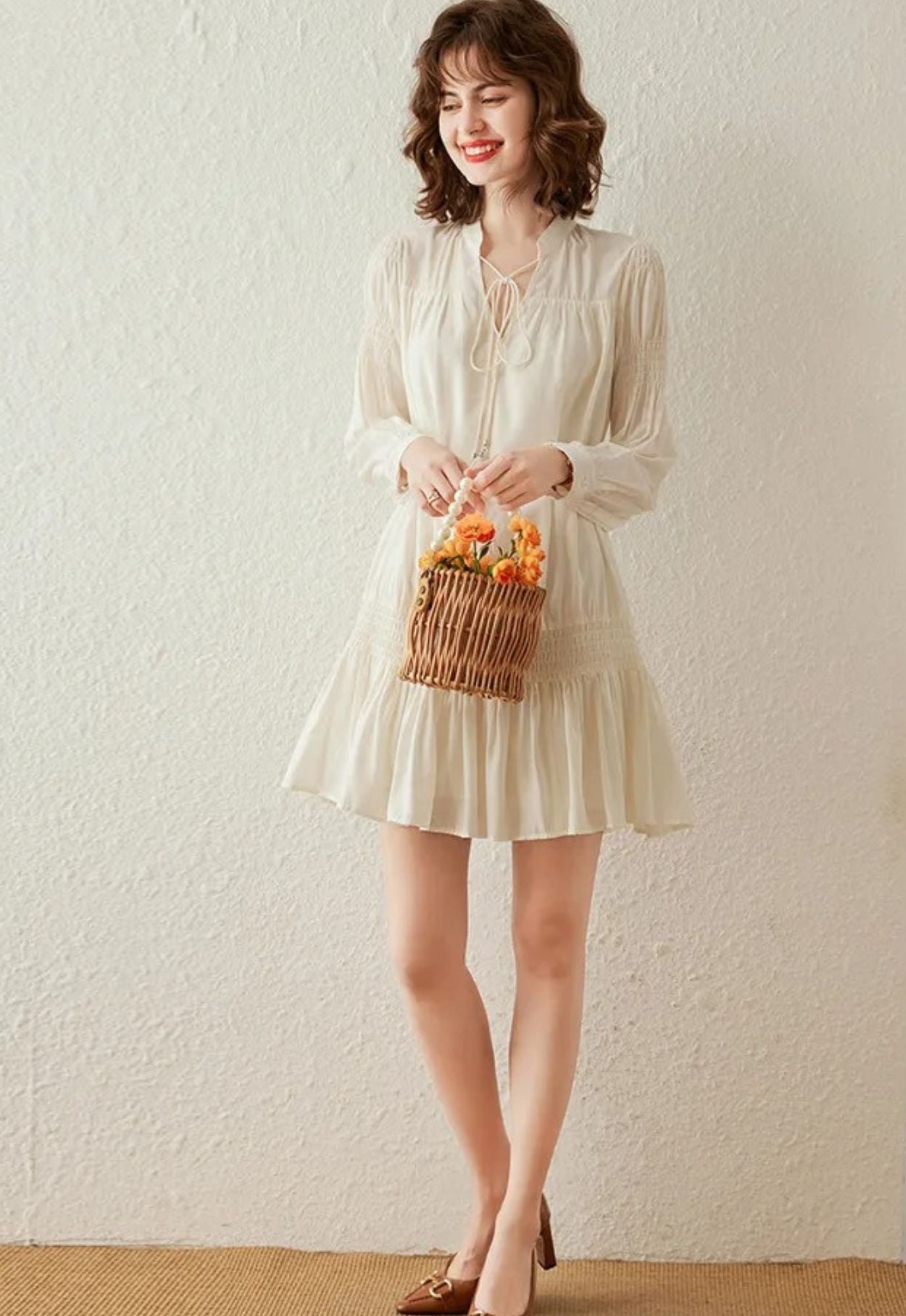 Full-body view of cream dress styled with woven handbag