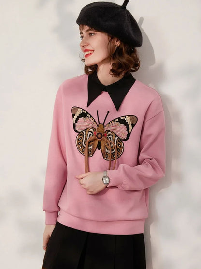 Side view of pink butterfly embroidered sweatshirt paired with a black skirt