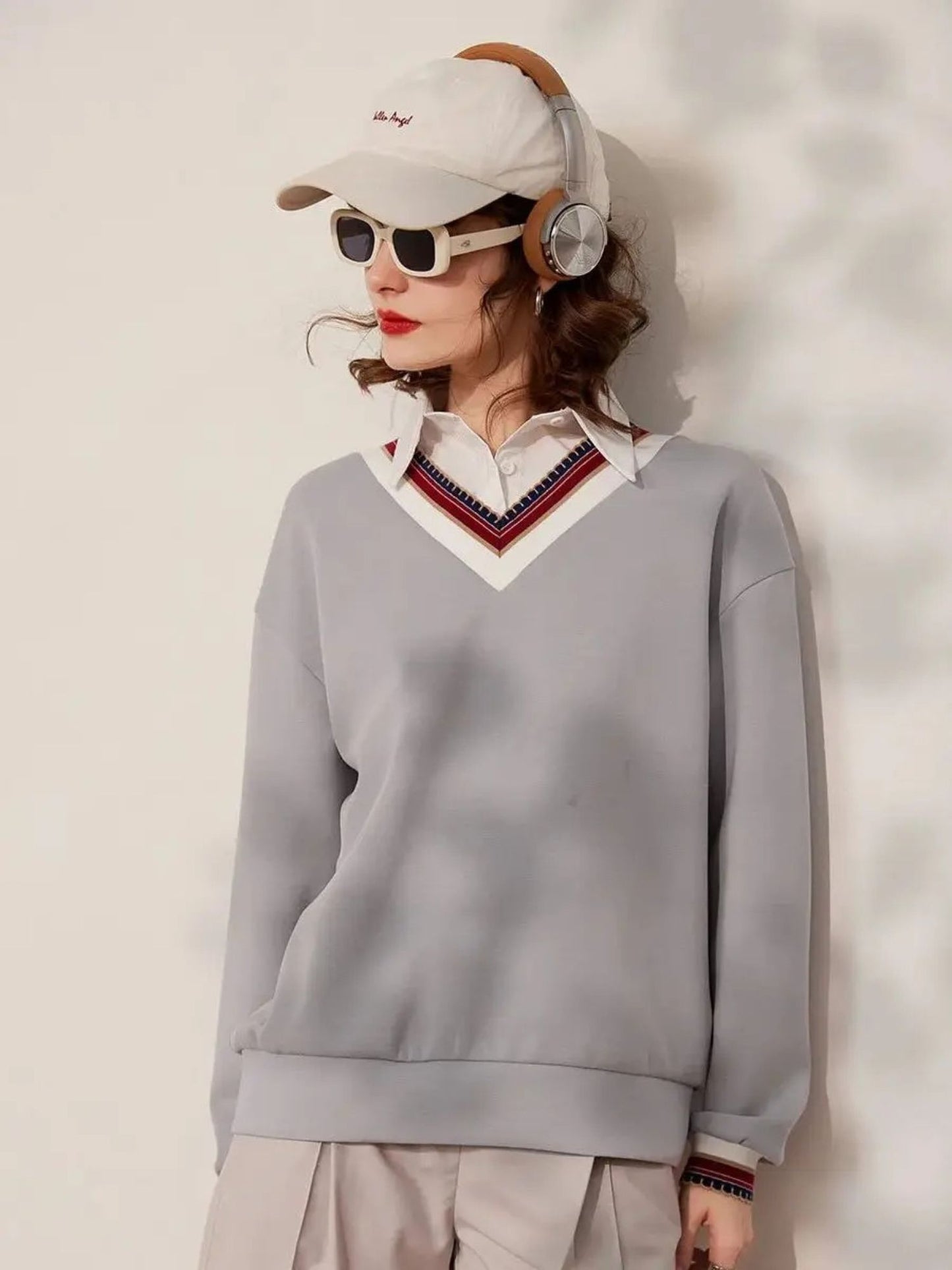 Front view of woman wearing grey V-neck sweatshirt with striped neckline