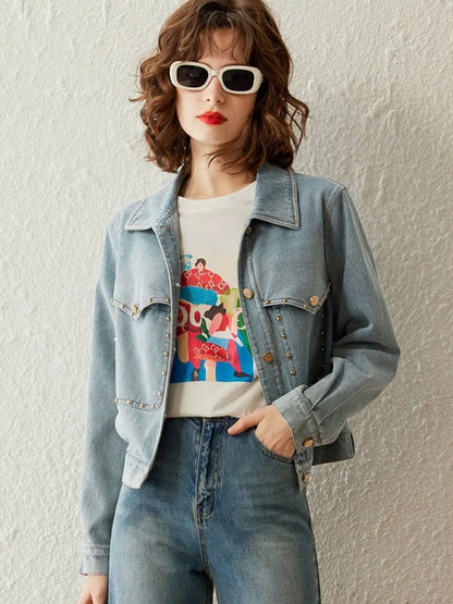 Woman in light blue denim jacket and jeans with printed t-shirt, standing with relaxed pose