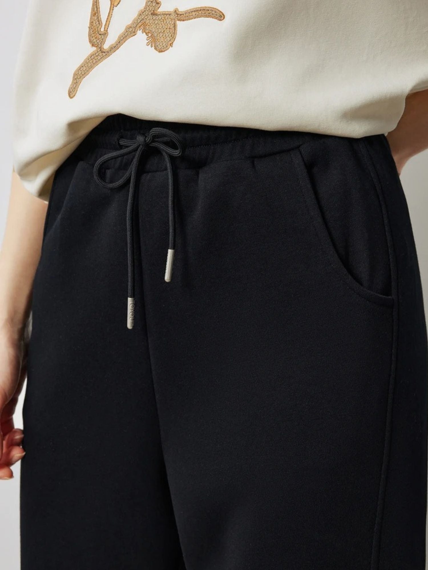 Close-up of black drawstring trousers with side pocket detail