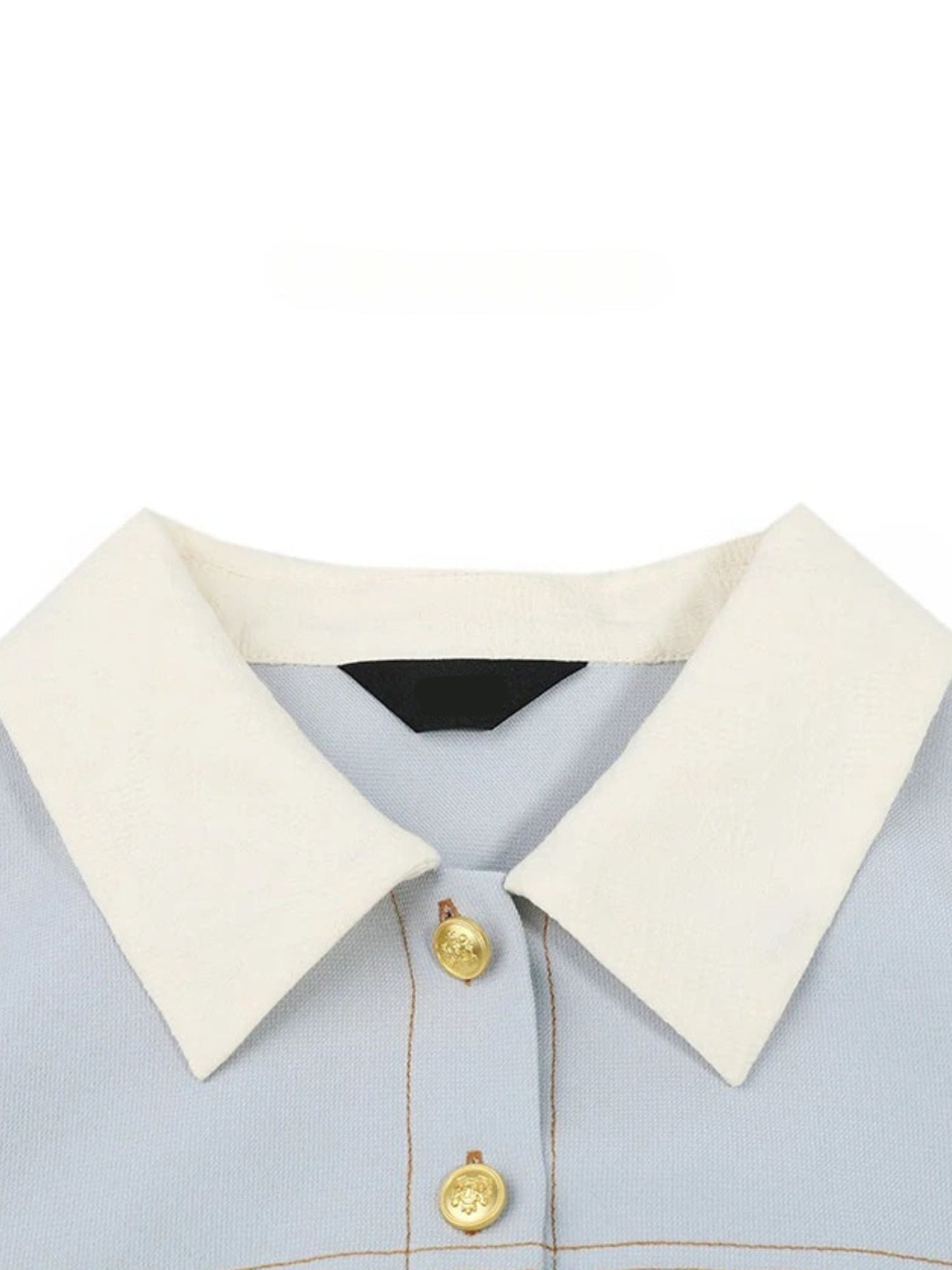 Close-up of white pointed collar and gold button detail