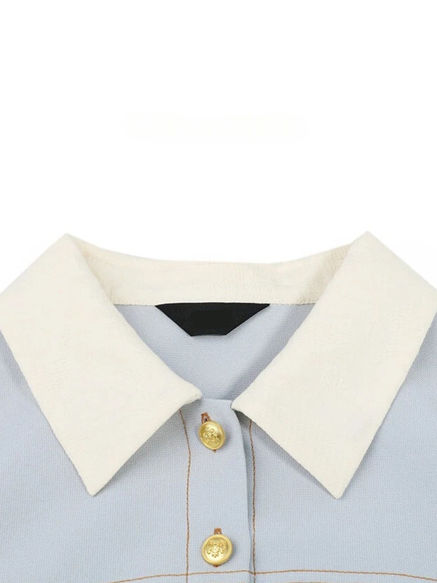 Close-up of white pointed collar and gold button detail
