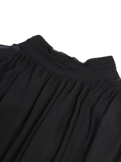 Close up of the neckline detail of black high-neck pleated midi dress