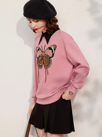 Angled view of pink sweatshirt with butterfly embroidery, styled with skirt